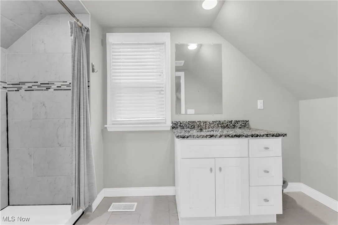 Full bathroom featuring lofted ceiling, a stall shower, vanity, and marble finish floors