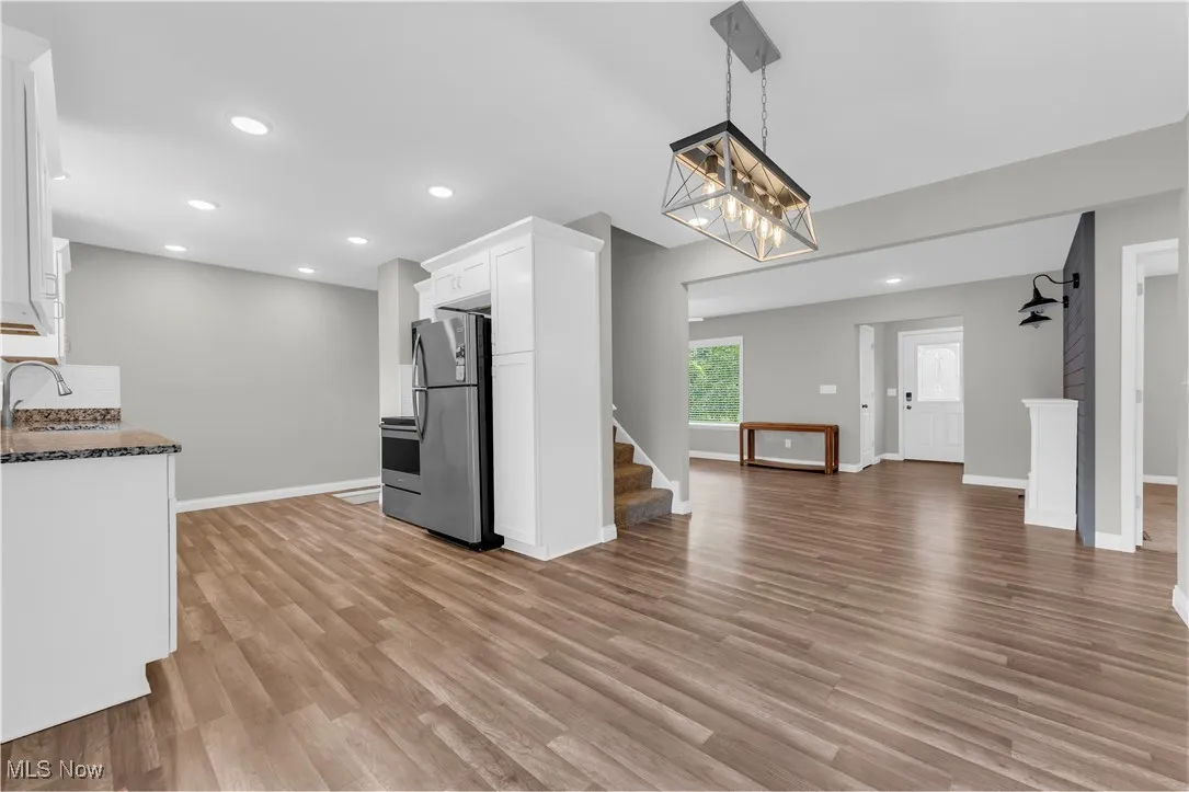 Kitchen with white cabinets, light wood-style floors, stainless steel appliances, recessed lighting, and open floor plan