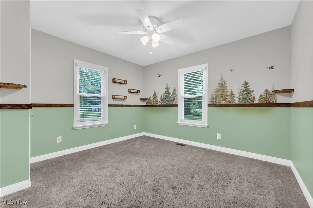 Unfurnished room with a ceiling fan, plenty of natural light, and carpet floors