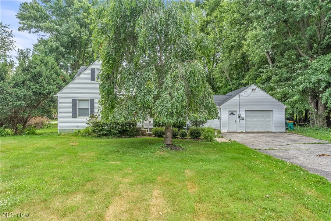 View of front of house featuring a garage, an outdoor structure, a front yard, and driveway