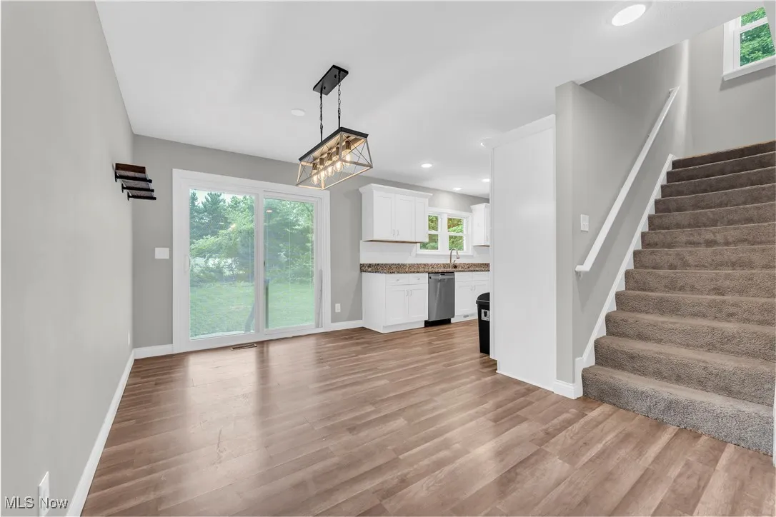 Unfurnished living room featuring stairs, light wood finished floors, healthy amount of natural light, and recessed lighting
