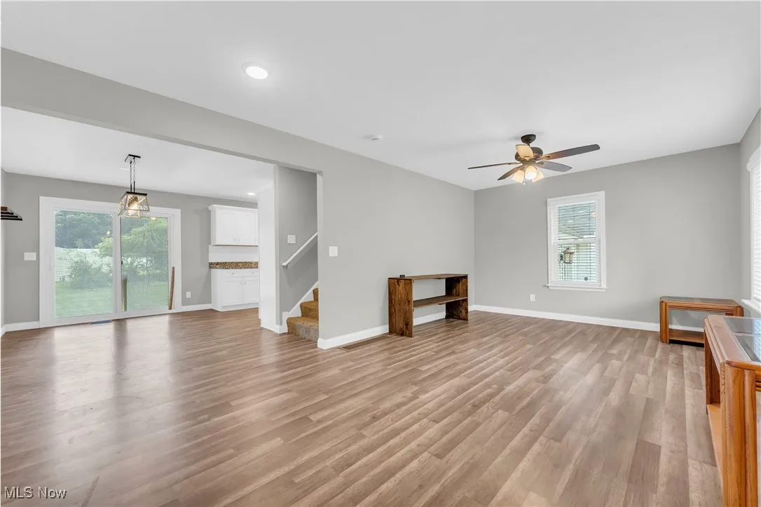 Unfurnished living room with light wood-style floors, stairway, a ceiling fan, and recessed lighting