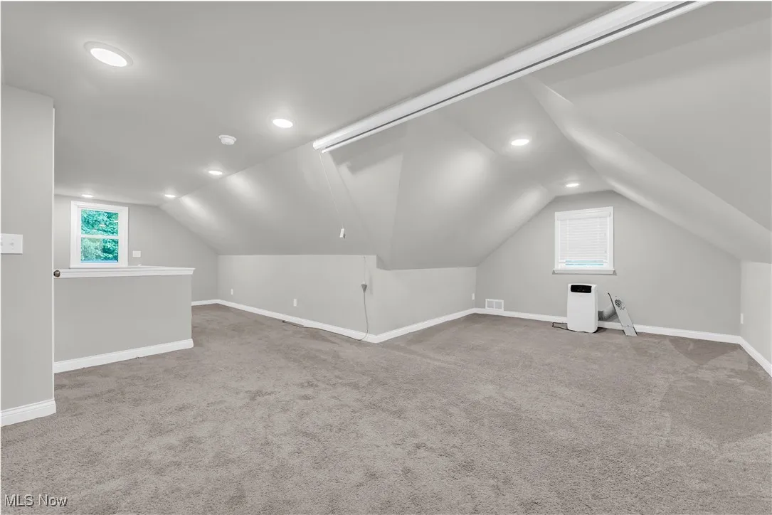 Additional living space featuring vaulted ceiling, carpet flooring, and recessed lighting