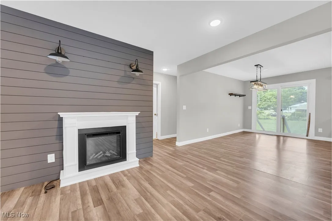 Unfurnished living room featuring recessed lighting, a glass covered fireplace, and light wood-style floors