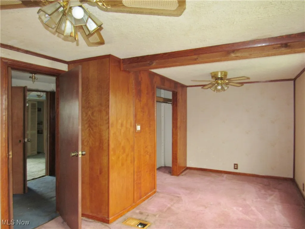 Spare room featuring a ceiling fan, light carpet, beam ceiling, and a textured ceiling