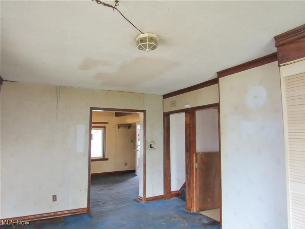Carpeted empty room with baseboards and stairs