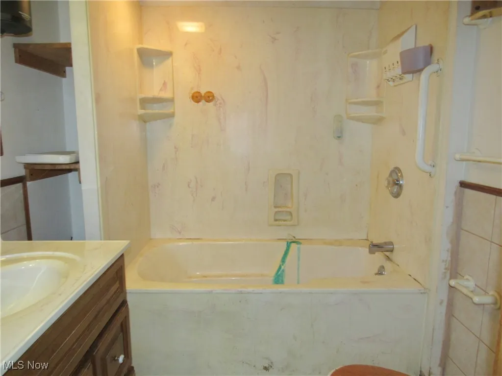 Full bathroom with vanity and a combined bath / shower with marble appearance