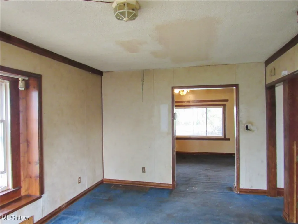 Carpeted spare room featuring baseboards and a textured ceiling
