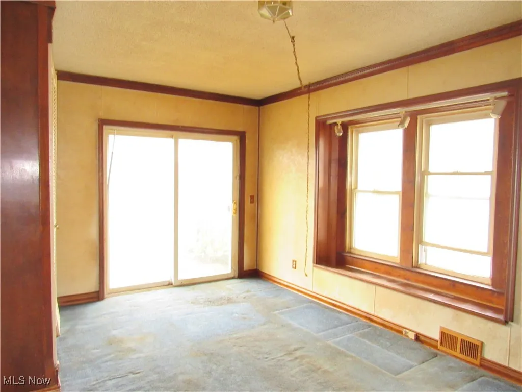 Carpeted empty room featuring ornamental molding and a textured ceiling