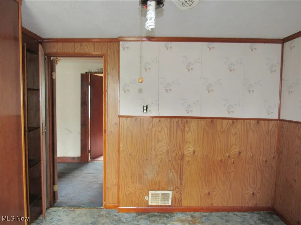 Spare room with ornamental molding, carpet floors, and wood walls