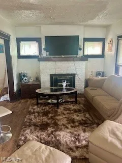 Living area featuring a tile fireplace, wood finished floors, a textured ceiling, and healthy amount of natural light