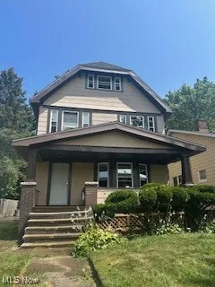 Traditional style home with covered porch and a front yard