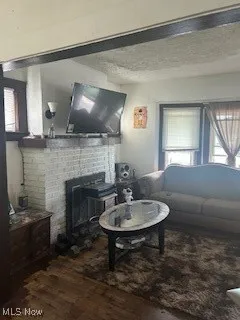 Living area featuring wood finished floors, plenty of natural light, a fireplace, and a textured ceiling