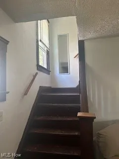 Stairway featuring a textured ceiling