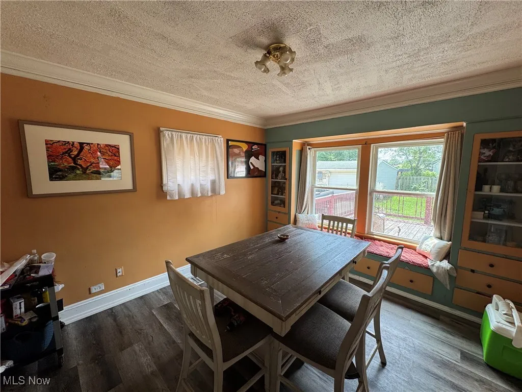 Dining area with a textured ceiling, crown molding, and dark wood finished floors