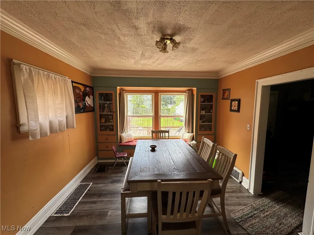 Dining area featuring a textured ceiling, crown molding, and dark wood finished floors