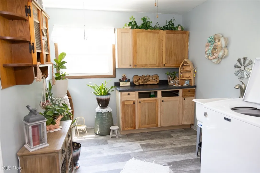 Laundry area featuring washer / dryer, cabinet space, and light wood finished floors