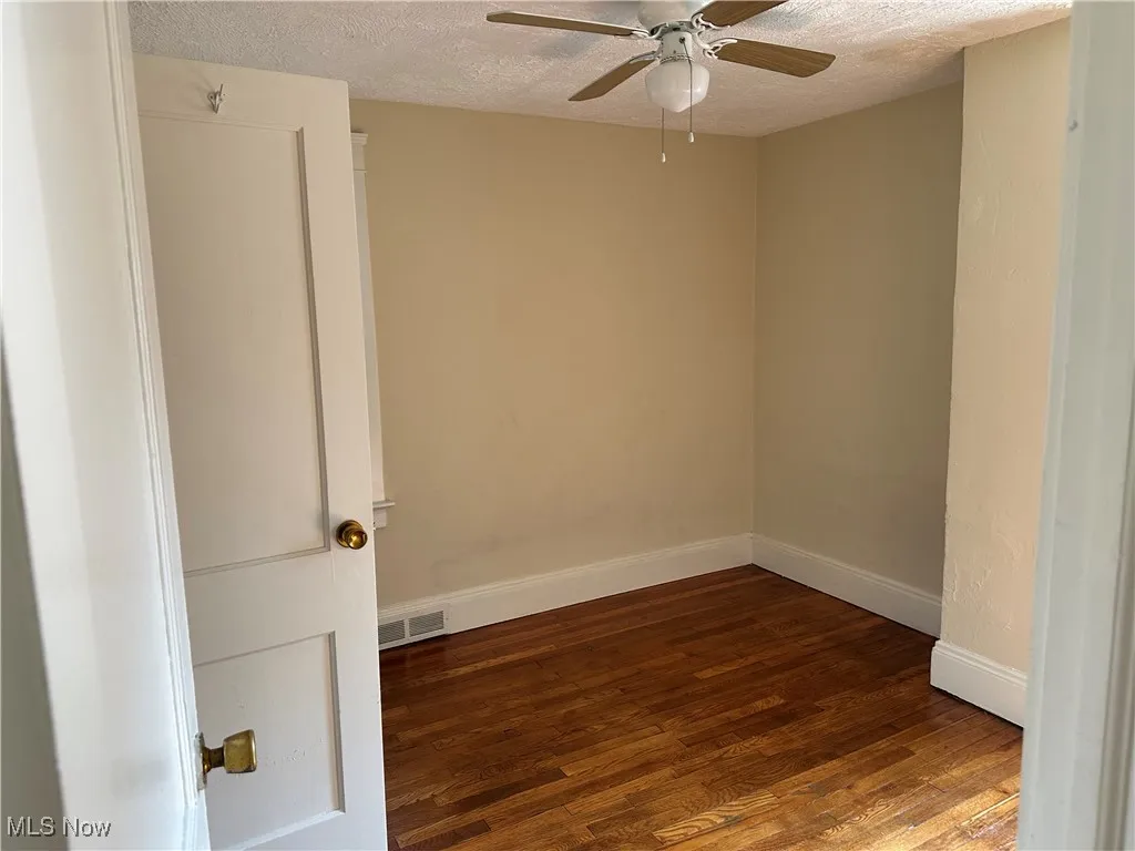 Unfurnished room featuring a textured ceiling, wood finished floors, and a ceiling fan