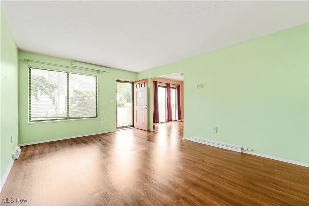 Empty room featuring wood finished floors, a baseboard heating unit, and a baseboard radiator