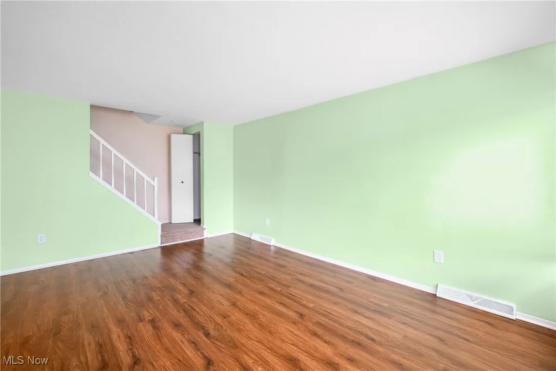 Spare room with dark wood-style floors and stairs