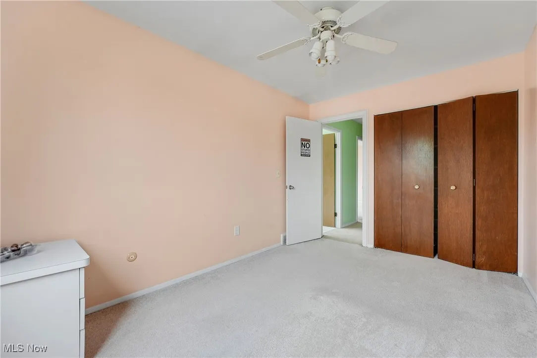 Unfurnished bedroom with light colored carpet, a ceiling fan, and a closet