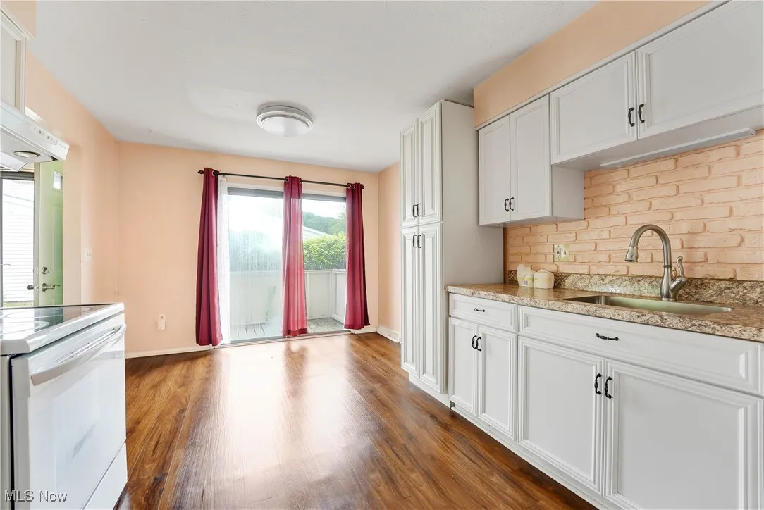 Kitchen with dark wood finished floors, tasteful backsplash, white cabinetry, light stone counters, and white electric stove
