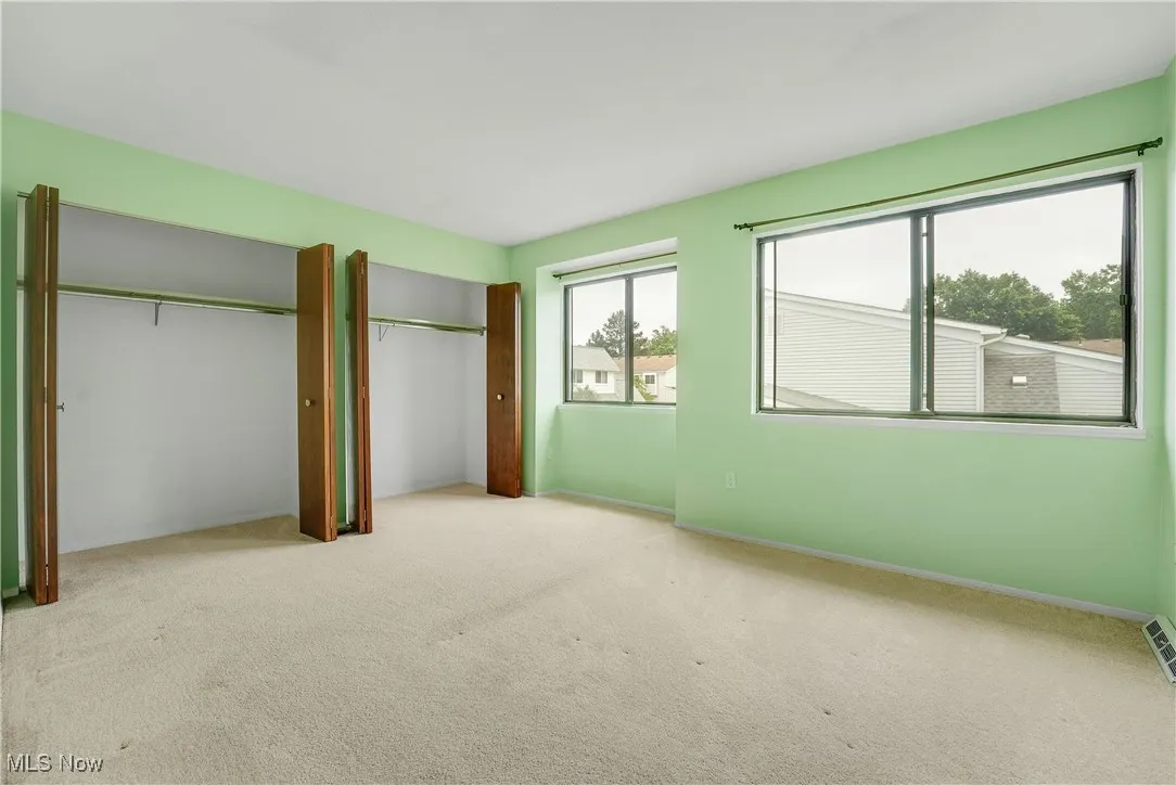 Unfurnished bedroom featuring carpet and multiple closets