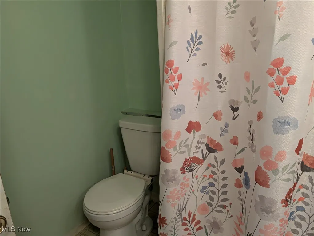 Bathroom featuring toilet and curtained shower