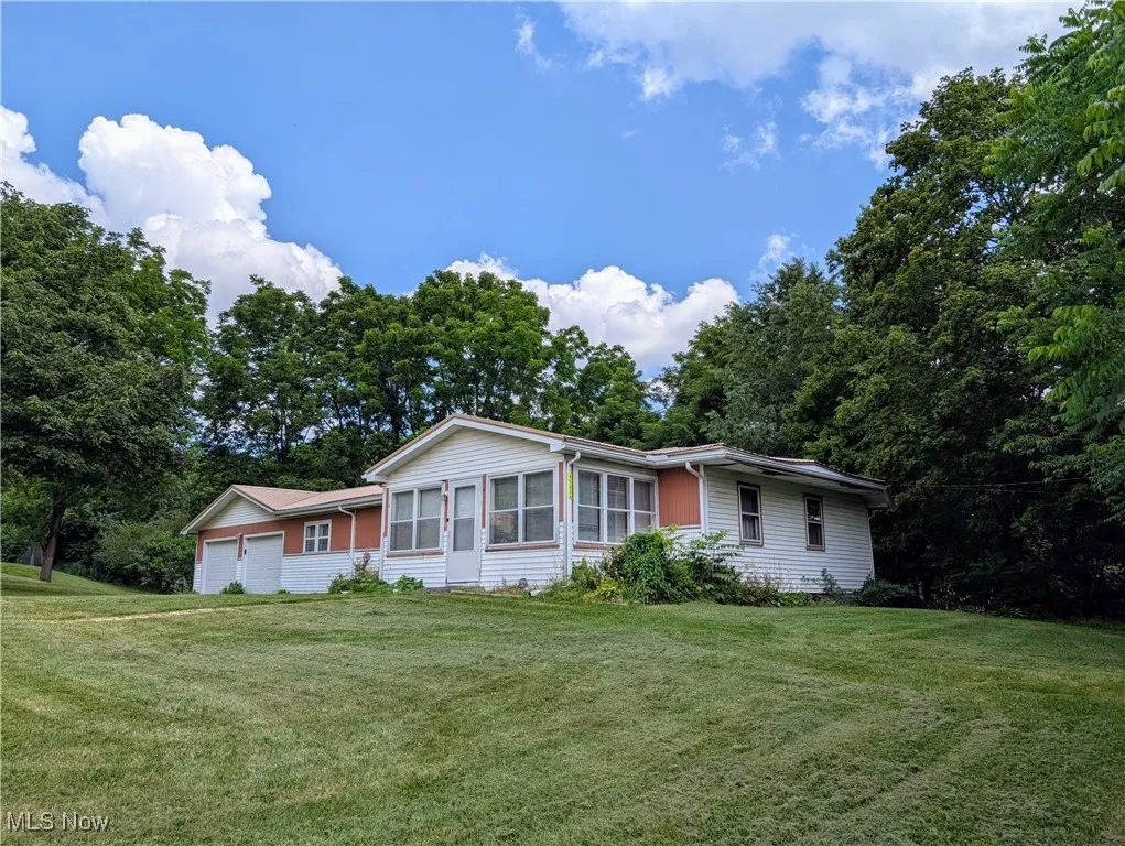 Ranch-style house with an attached garage, a front yard, and a sunroom