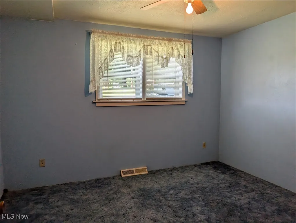 Carpeted empty room with a ceiling fan