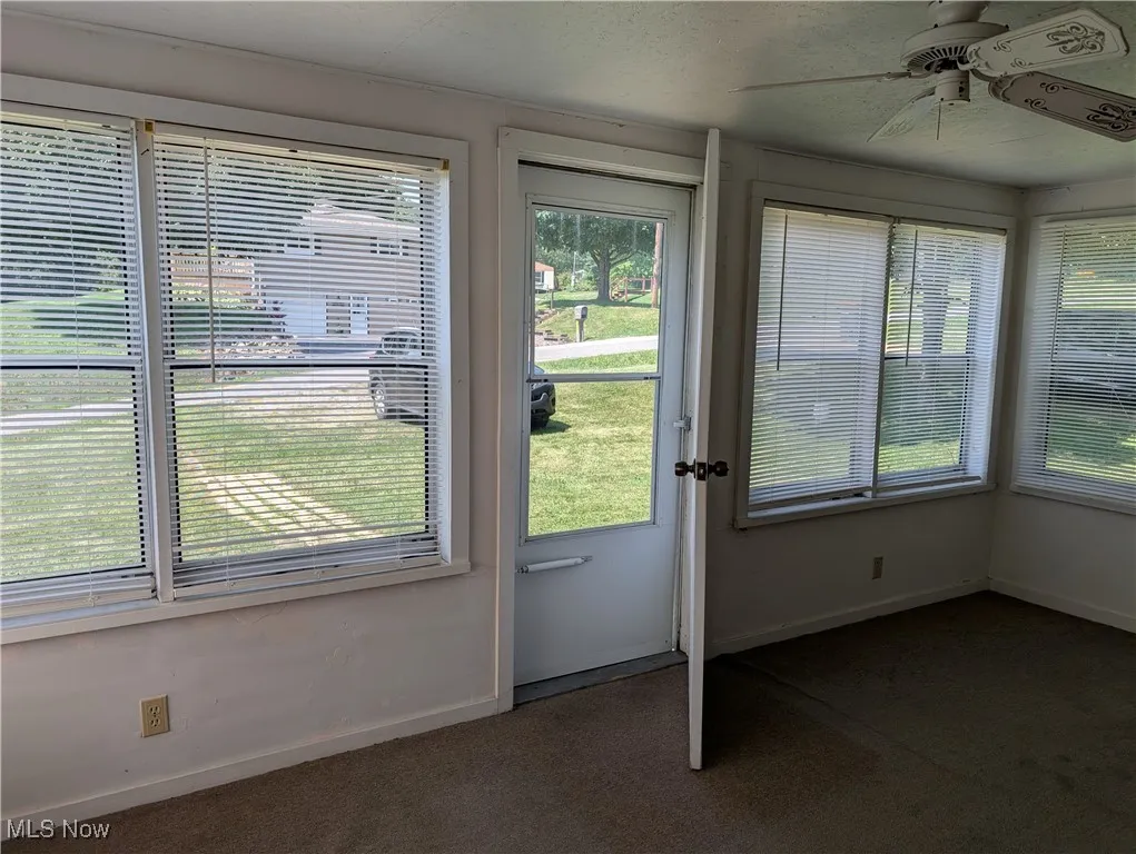 Entryway featuring dark carpet and a ceiling fan