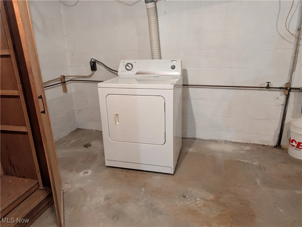 Washroom featuring washer / dryer and concrete block wall
