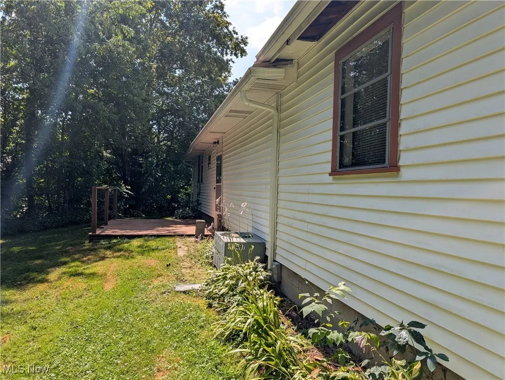 View of property exterior featuring a wooden deck and a yard