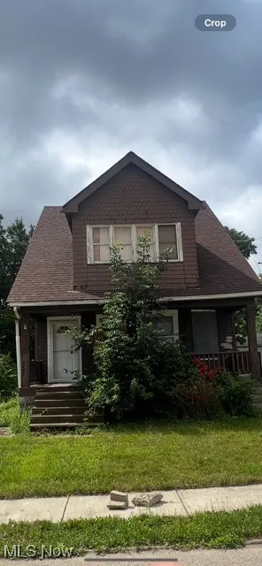 Bungalow with a shingled roof, a front yard, and covered porch