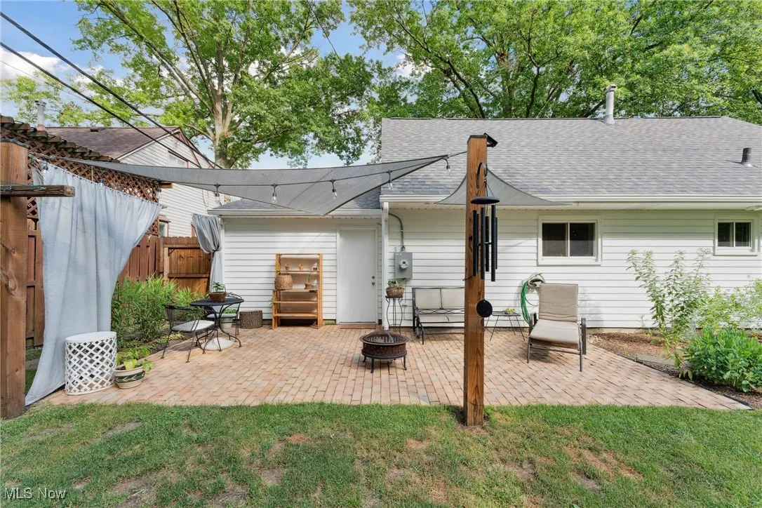 Rear view of house with an outdoor fire pit, roof with shingles, and a patio area