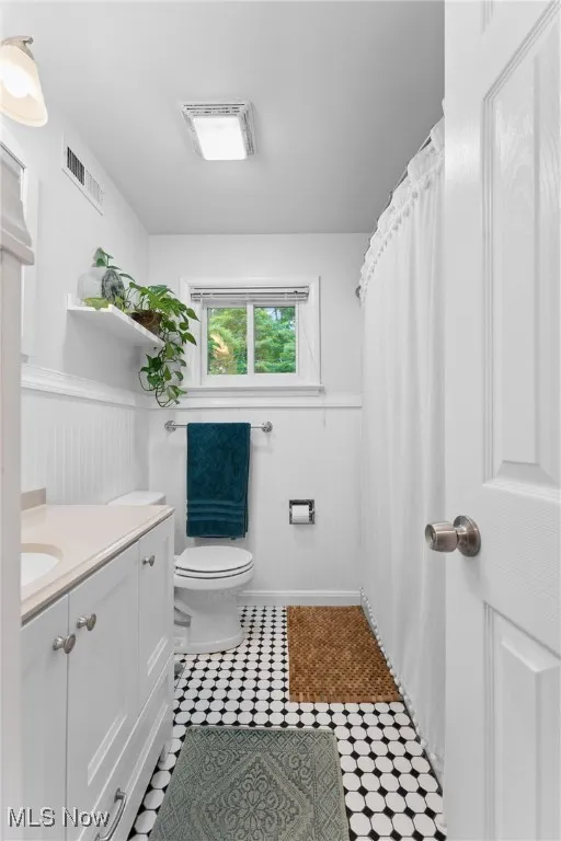 Full bath featuring wainscoting, vanity, and tile patterned flooring