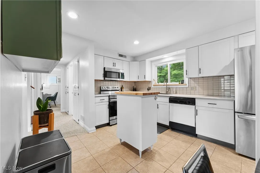 Kitchen featuring stainless steel appliances, white cabinetry, tasteful backsplash, light tile patterned floors, and recessed lighting