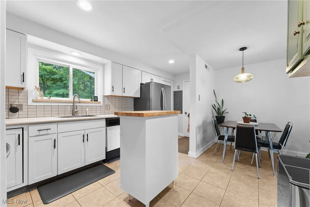 Kitchen featuring freestanding refrigerator, white dishwasher, decorative backsplash, white cabinetry, and recessed lighting