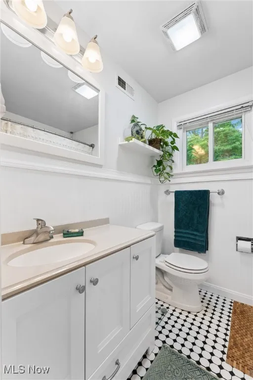 Bathroom with vanity, a wainscoted wall, and tile patterned flooring