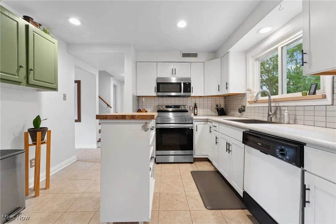 Kitchen featuring appliances with stainless steel finishes, tasteful backsplash, white cabinetry, and recessed lighting