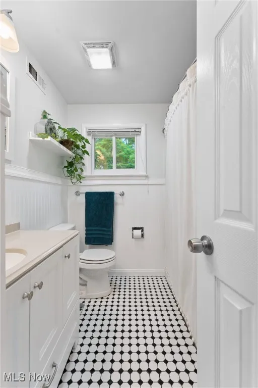 Full bathroom featuring wainscoting, vanity, and tile patterned flooring