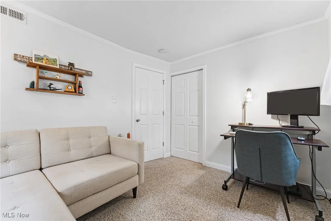 Carpeted office space with crown molding and baseboards