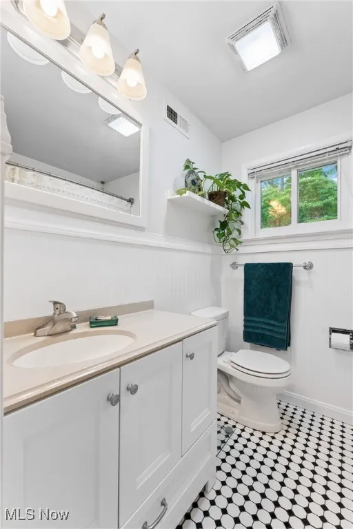 Bathroom featuring vanity, a wainscoted wall, and tile patterned flooring