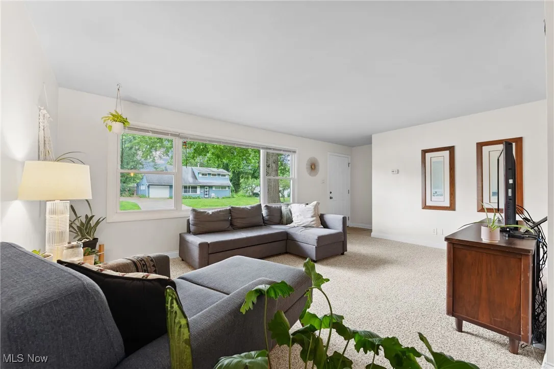 Living area featuring light colored carpet and baseboards