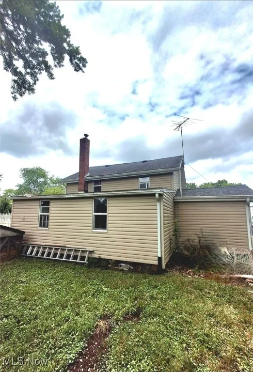 Back of house featuring a chimney and a yard