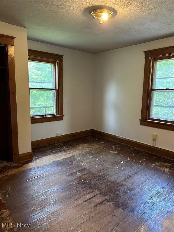 Empty room featuring hardwood / wood-style flooring and a textured ceiling