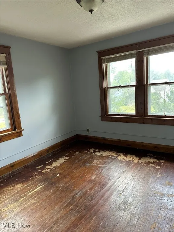 Unfurnished room with dark wood-style flooring and a textured ceiling
