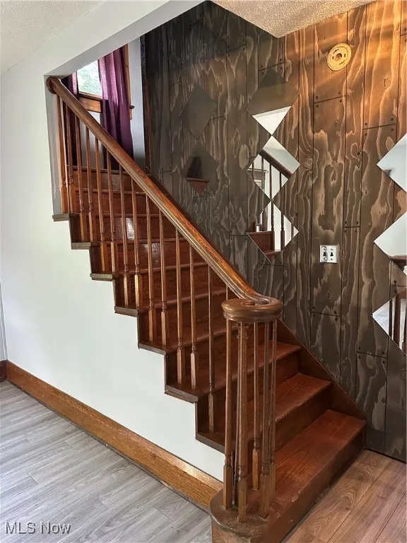 Staircase with wood finished floors and a textured ceiling