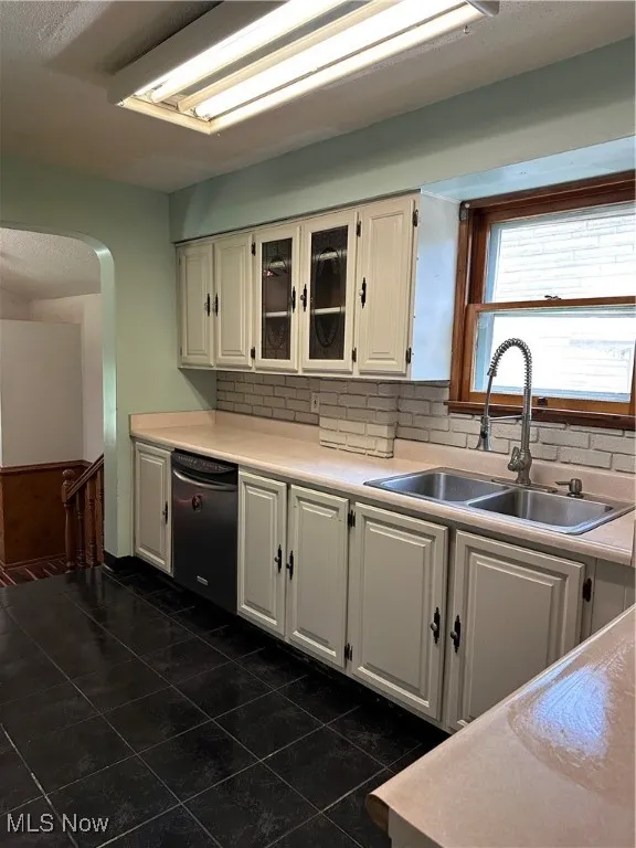 Kitchen with dark tile patterned floors, decorative backsplash, and light countertops