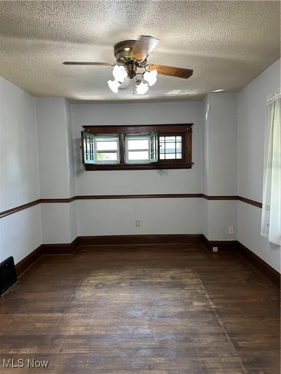 Empty room featuring wood finished floors, a textured ceiling, and a ceiling fan